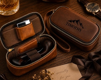 Puede incluir: Dos estuches de cuero marrón para pipa, uno abierto con una pipa y un encendedor, el otro cerrado con "TIMOTHY" y un gráfico de montaña. También se ven un reloj, un vaso de whisky y una tarjeta que dice "Especially for you".