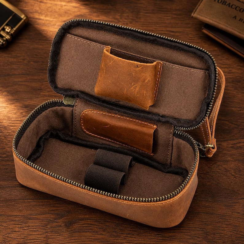 Puede incluir: Estuche de cuero marr&oacute;n abierto con cremallera, que revela un interior marr&oacute;n con bolsillos y bandas el&aacute;sticas. El estuche est&aacute; dise&ntilde;ado para guardar objetos peque&ntilde;os, con un aspecto robusto y texturizado.