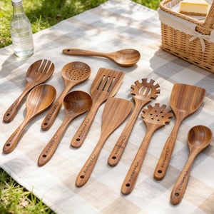 Może przedstawiać: Kolekcja drewnianych przyborów kuchennych, w tym łyżek, szpatułek i narzędzi szczelinowych. Przybory wykonane są z jasnobrązowego drewna i ułożone na piknikowym kocu w kratkę. Na każdym narzędziu znajduje się napis "Richard".