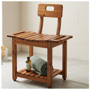 May include: A wooden shower bench with a backrest and a lower shelf. The bench is made of a warm-toned wood and features a slatted seat and back. A rolled green towel and a bottle of liquid are on the lower shelf. The bench is designed for bathroom use.