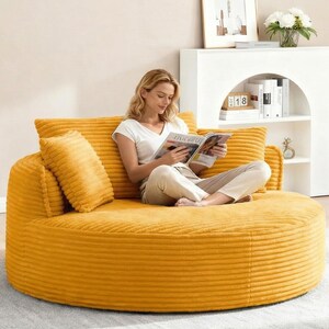 Puede incluir: Un sof&aacute; redondo de pana amarillo mostaza con dos cojines a juego y un respaldo. El sof&aacute; es una opci&oacute;n de asiento c&oacute;moda para una sala de estar o zona de descanso. La imagen muestra a una persona sentada en el sof&aacute; leyendo una revista.