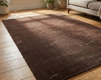 May include: A rectangular, dark brown rug with a textured surface. The rug is placed on a hardwood floor, and the overall aesthetic is warm and inviting. The rug is a solid color and appears to be made of a soft material.