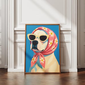 May include: A framed art print depicting a dog wearing sunglasses and a pink floral scarf against a blue backdrop. The dog has a cream-coloured coat and the frame is brown. The artwork is displayed on a wooden floor.