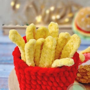 May include: A crocheted red basket filled with yellow fries. The image includes the text "Crochet pattern" and a "PDF" icon. The fries and basket are made of yarn, suggesting a handmade craft project.
