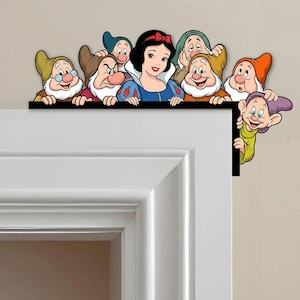 May include: A decorative door frame topper featuring Snow White and the Seven Dwarfs. The characters are depicted in their classic animated styles, with vibrant colors and detailed expressions. The topper is designed to fit over a door frame.