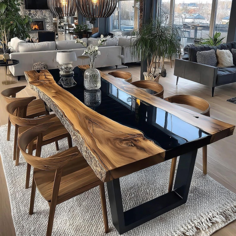 Op de afbeelding: Een moderne eettafel met een houten blad met levende rand en een zwart epoxyhars middenstuk. De tafel wordt ondersteund door zwarte metalen poten. Houten stoelen omringen de tafel. De kamer heeft een neutraal kleurenpalet.