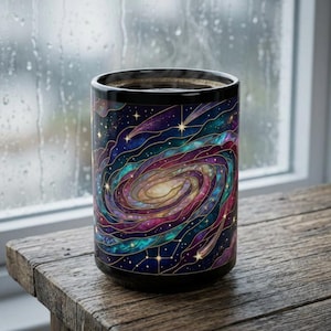 May include: A cylindrical mug featuring a vibrant galaxy design with swirling patterns of deep purple, blue, and teal colors. The surface is decorated with gold-toned lines that create a stained-glass effect, interspersed with small white stars.