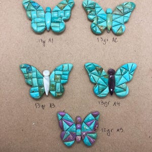 May include: Five turquoise butterfly-shaped stone carvings with mosaic-like patterns. The butterflies vary in color and design, with some featuring white or purple accents. Each butterfly has a weight measurement in grams.