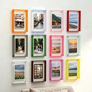 Puede incluir: Una cuadrícula de doce marcos de fotos rectangulares montados en la pared, cada uno con un borde de acrílico translúcido vibrante en colores que incluyen naranja, morado, rosa, rojo, gris, verde, azul, amarillo y blanco, mostrando varias fotografías.