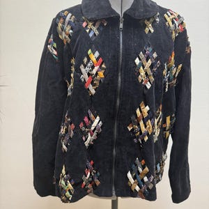 May include: Black corduroy jacket with a full-length zipper and a wide collar. The jacket features diamond-shaped woven fabric patches in various colors, including red, blue, and yellow. The jacket is displayed on a mannequin.