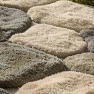 May include: Close-up of a textured rug with a stone-like pattern. The rug features various shades of gray and beige, creating a natural, organic look. The design resembles stepping stones or cobblestones, adding a touch of rustic charm to any space.