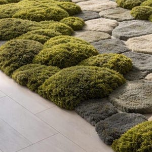 May include: A unique area rug with a textured design resembling stepping stones. The rug features a mix of green, gray, and beige tones, creating a natural, organic aesthetic. The plush, soft texture adds visual interest and comfort to any room.