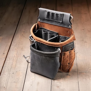 May include: A tool pouch constructed from brown and black leather, featuring multiple open compartments, a front pocket, and a top section with four small slots for tools. The pouch is secured with metal rivets and includes a metal loop on the side.