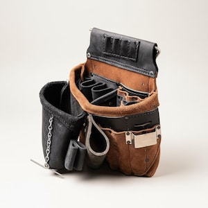 May include: A leather tool belt with multiple pockets and compartments. The belt features a combination of black and brown leather, with a metal clip and rivets. The open design reveals various slots for tools, and a small chain detail.