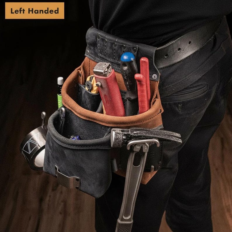 May include: A left-handed tool belt made of brown and black leather, featuring multiple pockets and loops. It holds a red utility knife, a black-handled screwdriver, a red tool, a silver hammer, and a roll of tape with a geometric pattern.