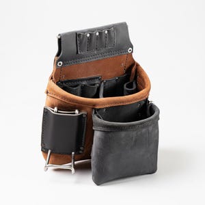 May include: A tool pouch constructed from tan and black leather, featuring multiple open compartments, internal pockets, a metal hammer loop on the side, and a reinforced top section with four small slots for holding hand tools securely.