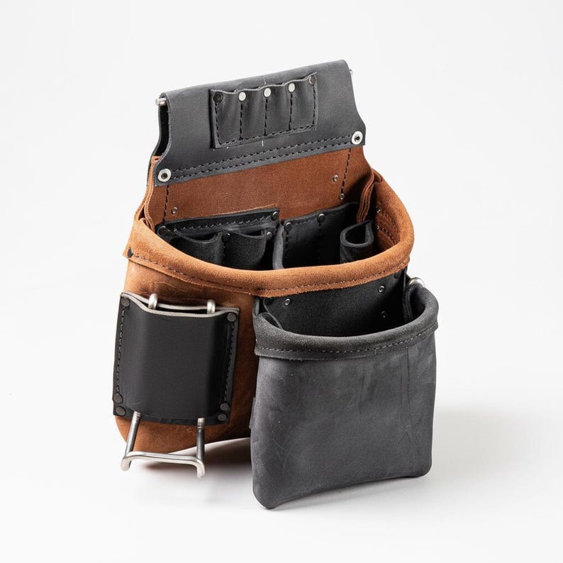 May include: A tool pouch constructed from tan and black leather, featuring multiple open compartments, internal pockets, a metal hammer loop on the side, and a reinforced top section with four small slots for holding hand tools securely.