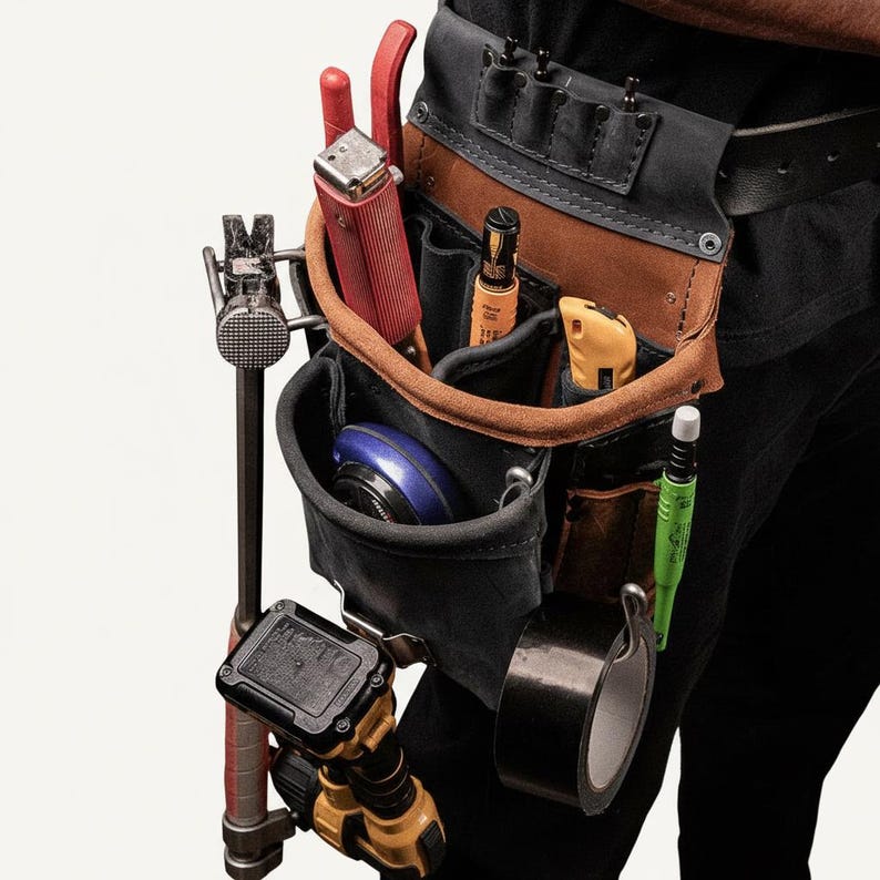 May include: A black and tan leather tool belt featuring multiple pockets and loops. It holds a red staple gun, a yellow utility knife, a green marker, a roll of black tape, a blue measuring tape, and a yellow power tool, with a hammer attached.