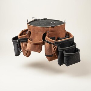 May include: A brown leather tool belt with multiple pockets and pouches. The belt has a circular top with a black interior and metal hardware. The pockets are various sizes and shapes, with some in black leather.