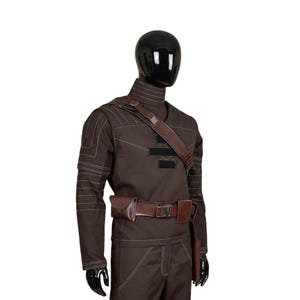 May include: A brown costume displayed on a mannequin. The outfit includes a long-sleeved top with white stitching, matching pants, a brown belt with a pouch, and a shoulder strap. The mannequin has a black head and hands.