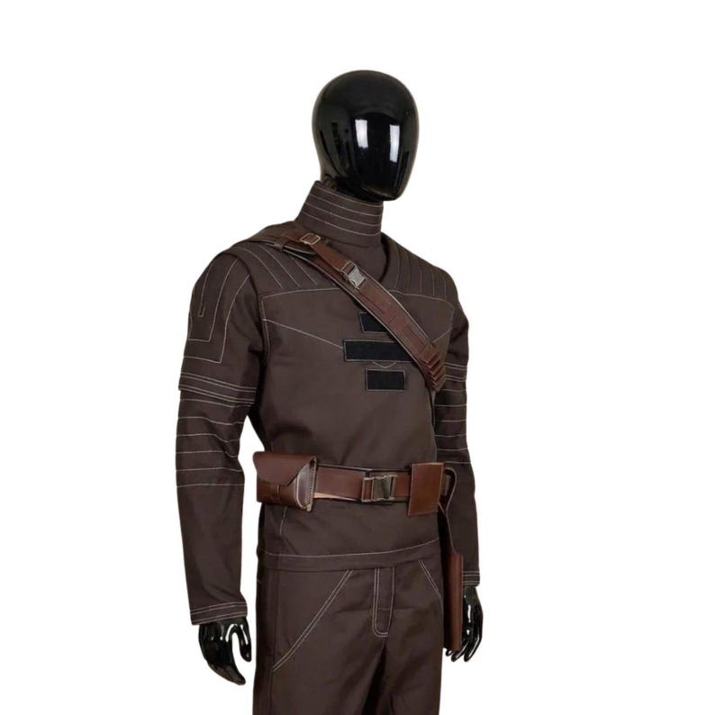 May include: A brown costume displayed on a mannequin. The outfit includes a long-sleeved top with white stitching, matching pants, a brown belt with a pouch, and a shoulder strap. The mannequin has a black head and hands.