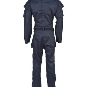 May include: A dark navy blue jumpsuit featuring a high collar, structured shoulder panels with ribbed detailing, long sleeves, and a waist belt. The garment includes cargo-style pockets on the thighs and a straight-leg cut, presented from the back view.