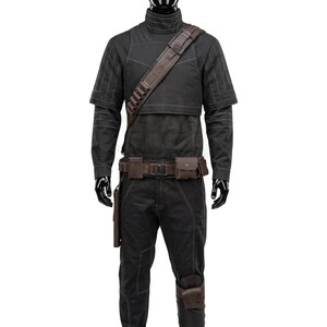 May include: A black long-sleeved shirt and matching pants set featuring white contrast stitching. The outfit includes a brown leather-like shoulder strap with ammunition loops, a utility belt with attached pouches, and a leg holster accessory.