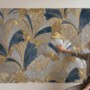 May include: A large wall art piece featuring a stylized floral design. The artwork showcases a pattern of large, leaf-like shapes in shades of blue, gold, and beige. The design has a textured appearance, with gold accents adding a touch of elegance.