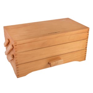 May include: A light brown wooden sewing box with a multi-tiered cantilever design and a hinged lid. The box features visible finger joints at the corners and the brand name Milward is printed in small black letters on the top surface.
