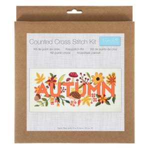 Może przedstawiać: Zestaw do haftu krzyżykowego Trimits w brązowym kartonowym pudełku. Etykieta zawiera napis Counted Cross Stitch Kit oraz ilustrację słowa AUTUMN w otoczeniu kolorowych jesiennych liści, kwiatów, grzybów i jeża.