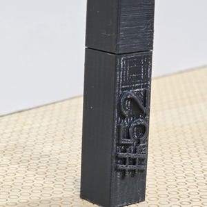 May include: A black, rectangular USB flash drive with a textured surface. The drive has a removable cap and features the word "LOVE" embossed on its side. The design includes a grid pattern below the word.