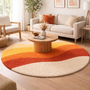 Op de afbeelding: Een rond tapijt met een retro-ontwerp. Het tapijt heeft horizontale banden in crème, geel, oranje en rood. Het tapijt staat in een woonkamer met een bank, stoelen en een salontafel. De tekst "ELITE CRAFTED RUGS" staat onderaan.
