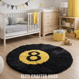 May include: A circular black rug featuring a yellow number 8 design. The rug is placed in a nursery, alongside a white cot, chest of drawers, and a bookshelf. The text "ELITE CRAFTED RUGS" is visible at the bottom.