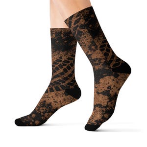 May include: Crew socks with a brown and black tire track pattern. The socks have black heels and toes, and the design covers the entire sock. The brown color has a speckled effect, adding texture to the design.