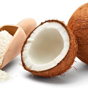 Image of whole, halved Coconut next to a wooden serving spoon containing shredded coconut.