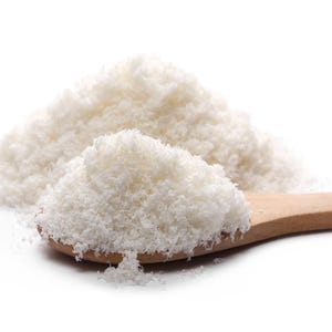 Closeup image Shredded coconut on a wooden spoon on a white background.