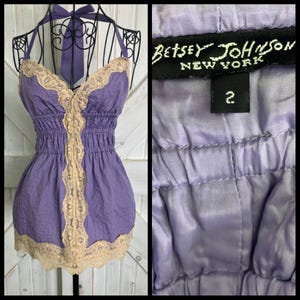 Può includere: Un top Betsey Johnson color lavanda con collo all'americana e vita aderente. Il top presenta finiture in pizzo beige lungo lo scollo, il centro e l'orlo. L'etichetta recita "Betsey Johnson New York" e taglia 2.
