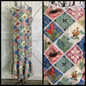 May include: A sleeveless, floor-length dress with a patchwork design featuring turtles, flowers, and birds. The dress has a white lace trim around the neckline and a ruffled hem. The colour palette includes blue, green, pink, and cream.