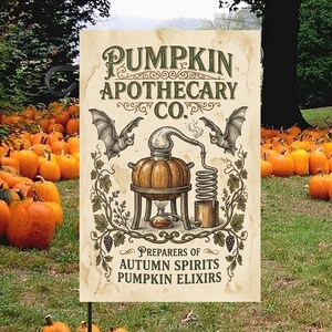 Peut inclure: Un drapeau de jardin rectangulaire sur fond crème portant le texte PUMPKIN APOTHECARY CO. et PREPARERS OF AUTUMN SPIRITS PUMPKIN ELIXIRS. Le motif comprend un alambic en forme de citrouille au centre, deux chauves-souris et des vignes décoratives.