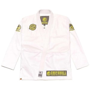 May include: White martial arts gi with the text "SHOYOROLL" in yellow and black. The gi features a collar, lapels, and a belt. Patches with the brand logo are on the sleeves and chest. The uniform is designed for martial arts training.