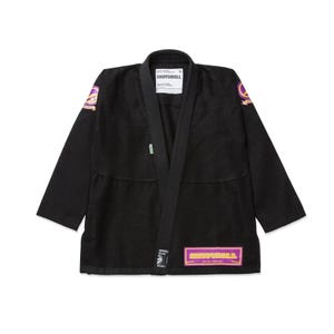 May include: Black martial arts gi with a lapel collar. The gi features the brand name "SHOYOROLL" on a label and patch. The gi has purple and gold accents on the shoulders and a patch near the bottom. The gi is designed for martial arts training.