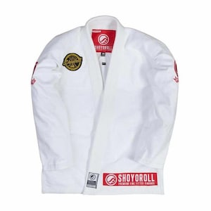 May include: White martial arts uniform with the brand name "SHOYOROLL" in red. The uniform has a gold and black patch on the left shoulder and red accents on the sleeves. The uniform is a premium fine-fitted kimono.