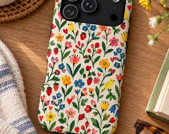 May include: A smartphone case with a cream-colored background featuring a repeating pattern of small red strawberries, tiny red hearts, blue and yellow flowers, green leaves, and small yellow birds. The case has a black camera cutout area.