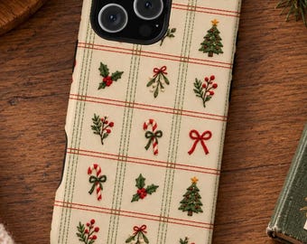 May include: A cream-colored phone case featuring a grid pattern of thin green and red lines. The design includes embroidered-style icons of red bows, green Christmas trees with yellow stars, holly berries, mistletoe, and candy canes.