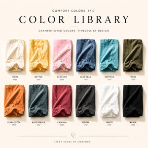 Puede incluir: Una biblioteca de colores Comfort Colors 1717 que muestra doce muestras de tela dobladas en marfil, mantequilla, flor, azul vaquero, espuma de mar, musgo, terracota, abeto azul, carmes&iacute;, pimienta, blanco y negro, con etiquetas para cada color.
