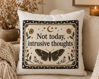May include: A square white throw pillow featuring a central rectangular graphic with a black and gold mosaic-style border. The text reads Not today, intrusive thoughts, accompanied by a moth illustration, a crescent moon, and floral motifs.