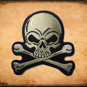 May include: Embroidered skull and crossbones patch in beige and black. The skull has detailed stitching and is set against a black background. The patch is on a vintage-style, textured background.