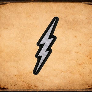 May include: A silver lightning bolt patch with a black border, set against a vintage-style, textured tan background. The patch is a stylized zig-zag shape, commonly associated with energy and power. The background has a decorative border.