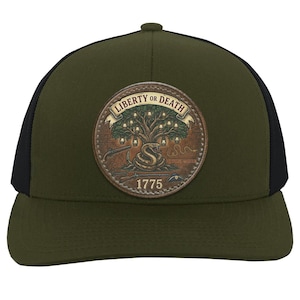 May include: An olive green baseball cap with black mesh side panels and a circular patch on the front. The patch features a tree with lanterns, a coiled rattlesnake, firearms, and the text Liberty or Death with the year 1775 printed below.