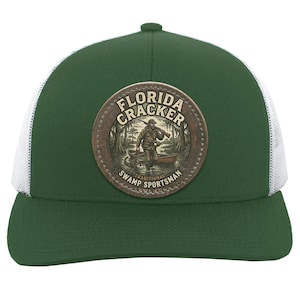 Puede incluir: Gorra de camionero verde y blanca con un parche circular. El parche muestra las palabras "Florida Cracker Traditional Swamp Sportsman Since 1821" y una ilustración de una persona en un bote en un pantano.